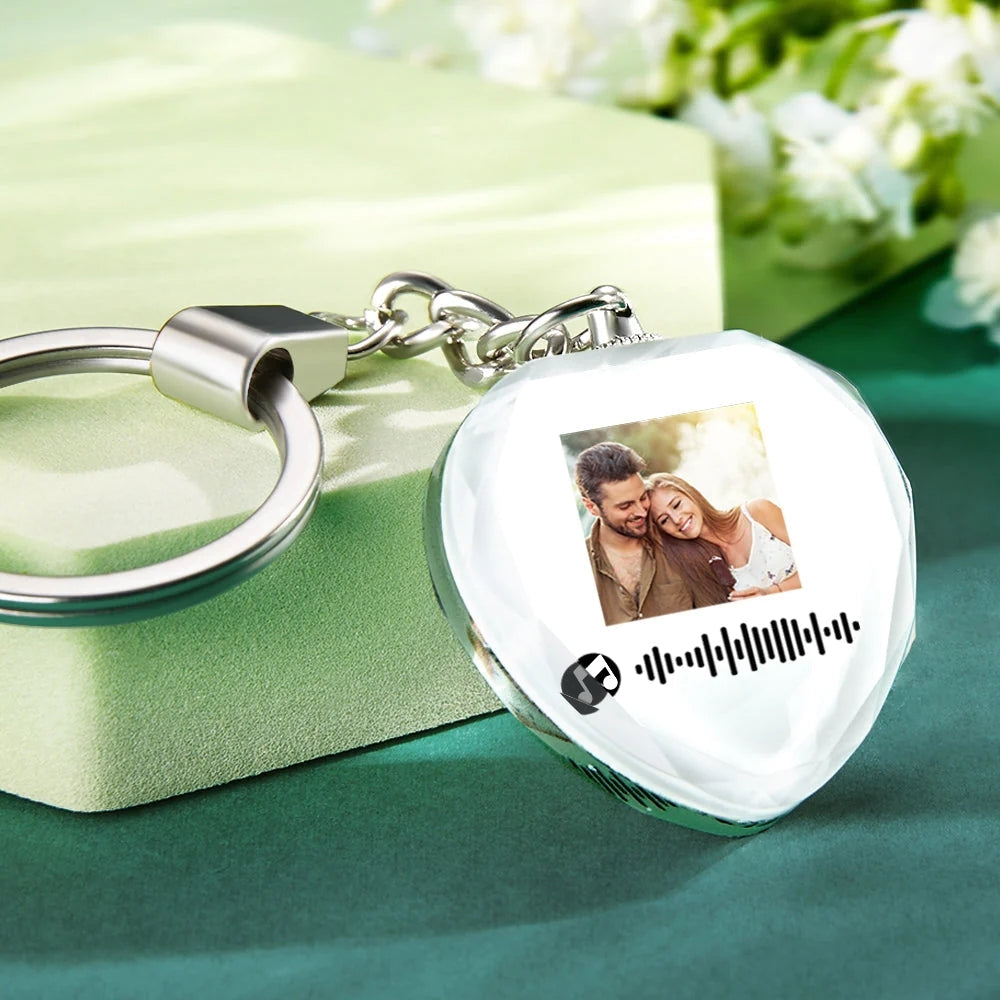 Crystal keychain on wooden surface showing engraved image and visible scannable music code — personalised keepsake