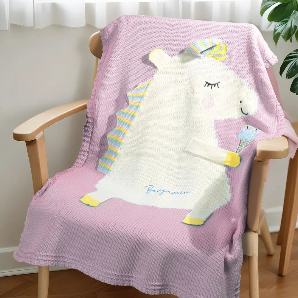 Full view of the knitted unicorn blanket with embroidered name laid flat