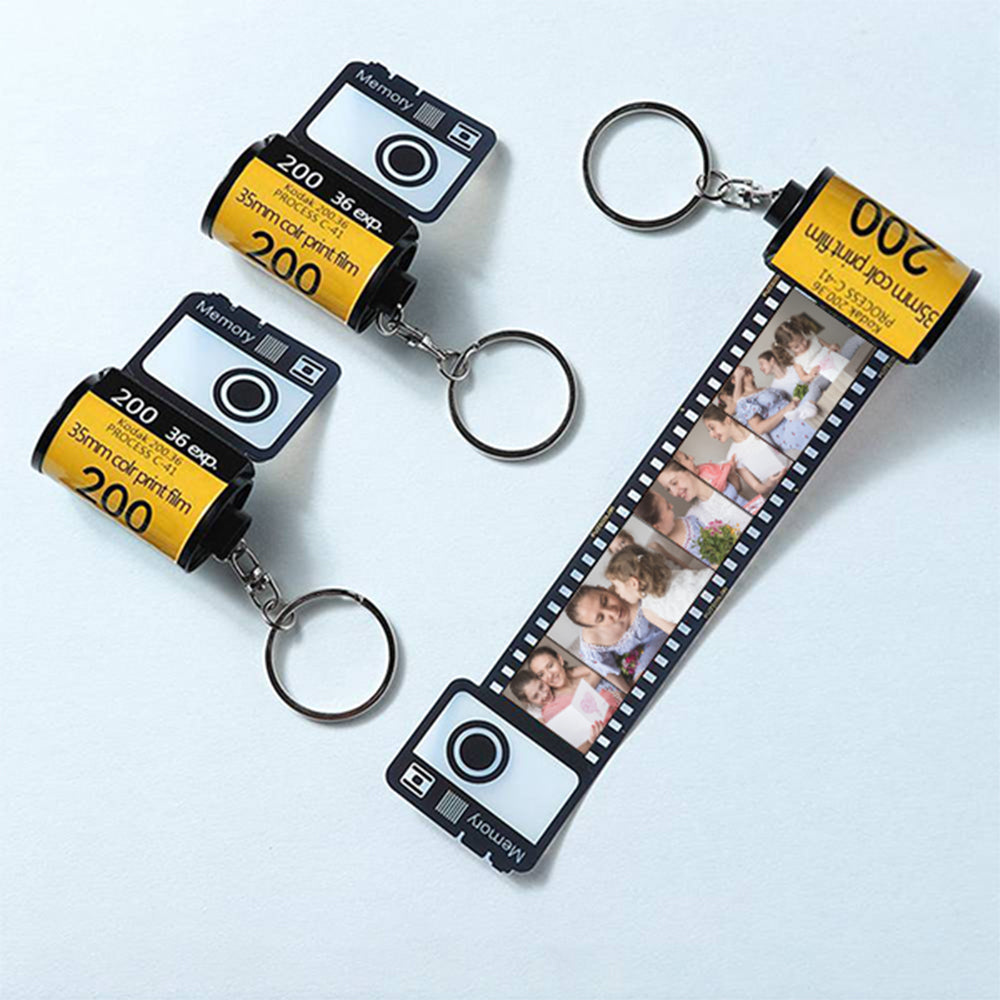 The personalised camera film-roll keychain presented in its hardcover gift box.