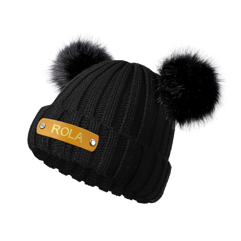 Stacked personalised baby beanies in assorted colours, each with a custom hot-stamped leather name patch for boys and girls