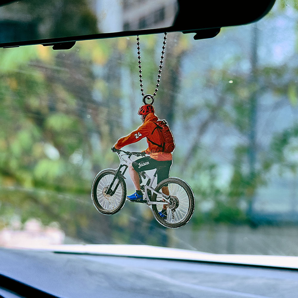 Close-up of personalised engraved mountain bike ornament hanging on a Christmas tree — acrylic cycling gift for trail riders