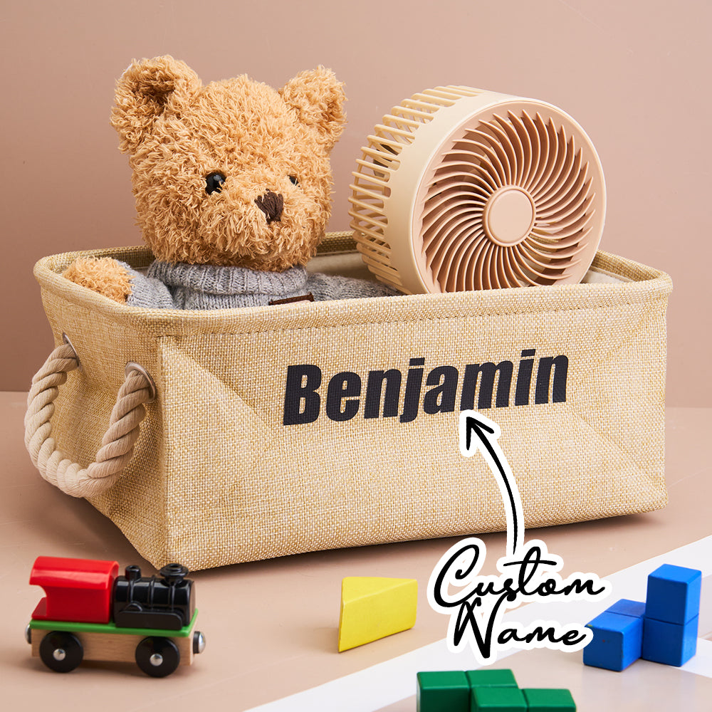 Personalised linen toy storage basket with name displayed in a nursery; open-top organiser for soft toys and books in neutral linen.
