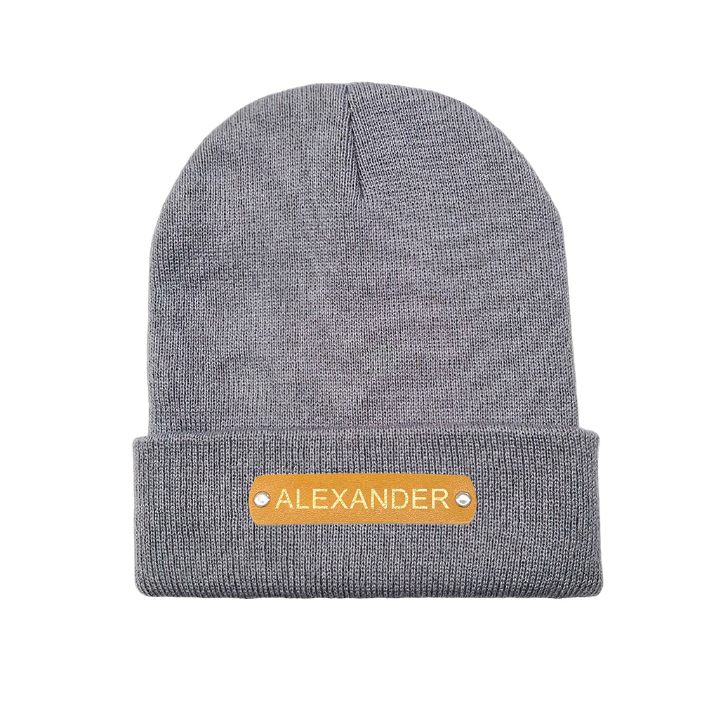 Close-up of hot-stamped custom name on leather patch showing crisp embossed lettering on the personalised beanie