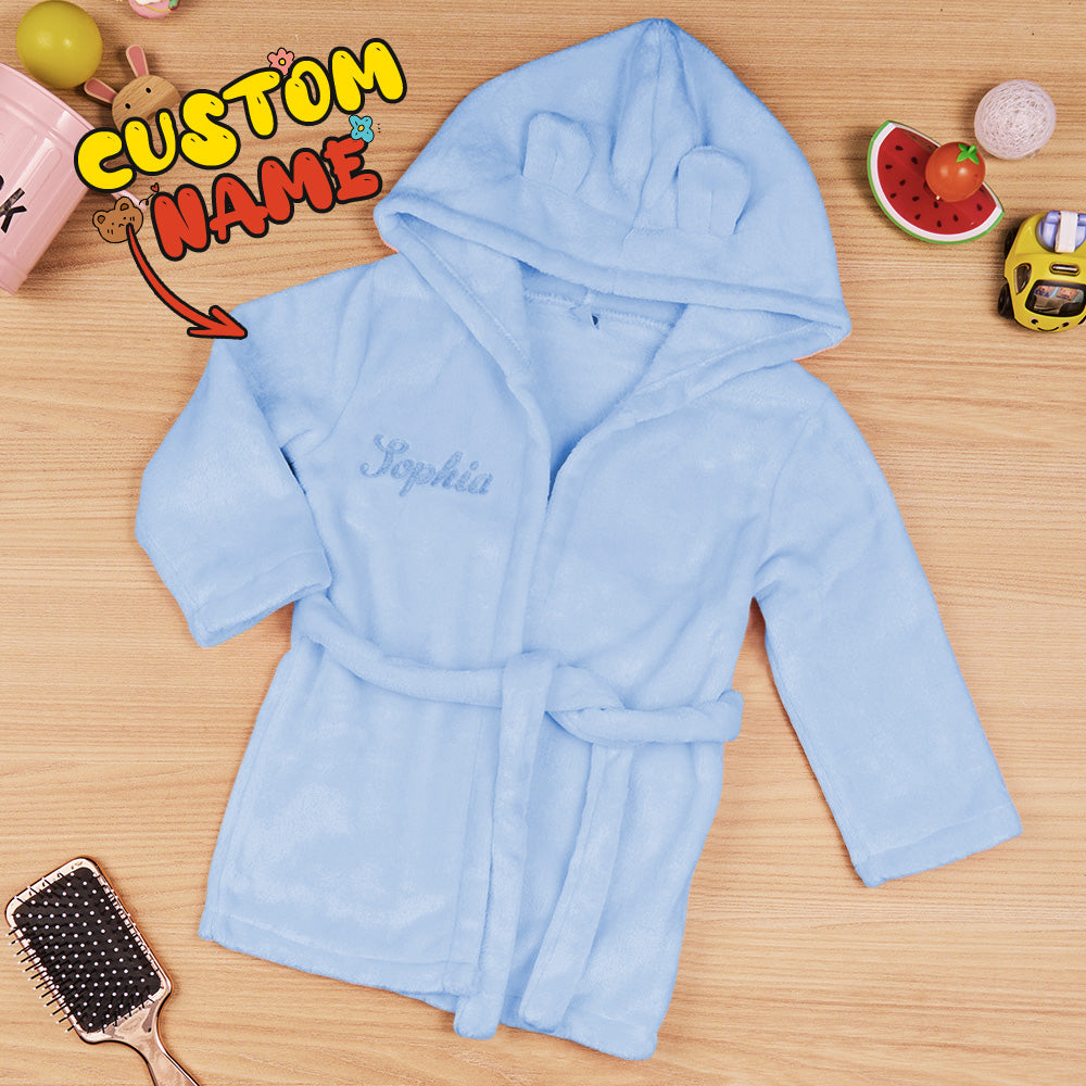 Smiling baby wearing a personalised dressing gown with embroidered name and hooded bear ears, ideal for christenings and first birthdays