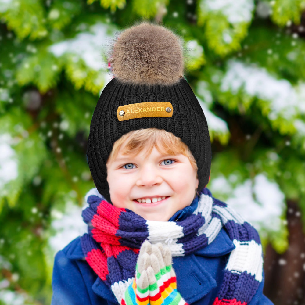 Leather patch detail with hot-stamped name on personalised beanie — durable engraved finish for a timeless baby gift