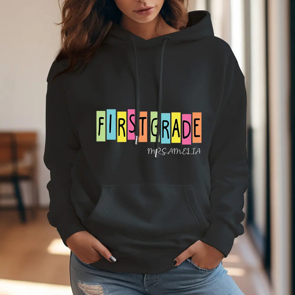 Teacher modelling personalised first grade hooded sweatshirt in classroom — comfortable polyester personalised teacher hoodie for everyday wear.