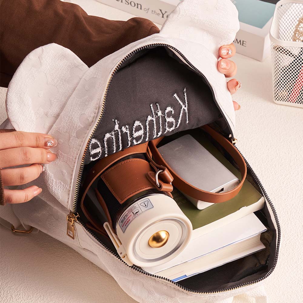 Close-up of name embroidery and delicate floral stitching on personalised mini canvas backpack — high-quality custom embroidery detail