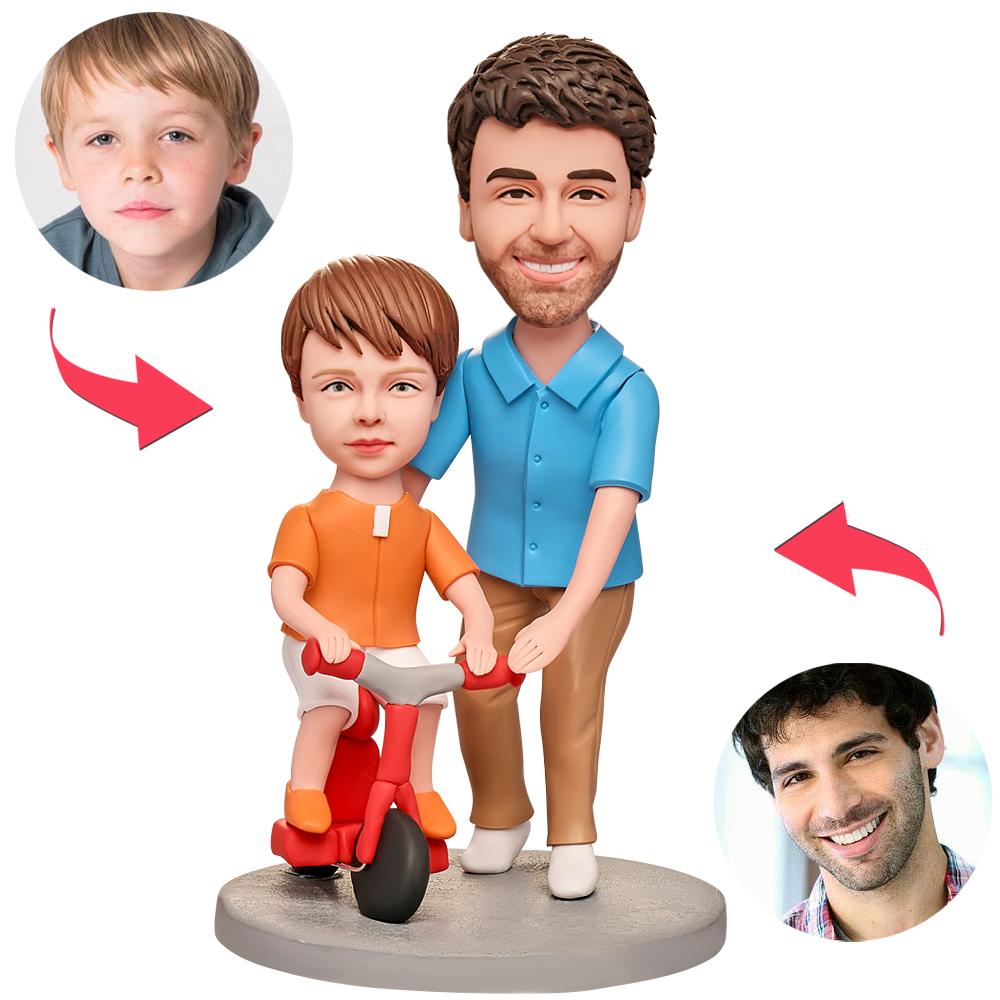 Close-up of personalised dad teaching son cycling bobblehead showing detailed facial customisation, fine polymer‑clay sculpting and engraved message on the base for a bespoke keepsake