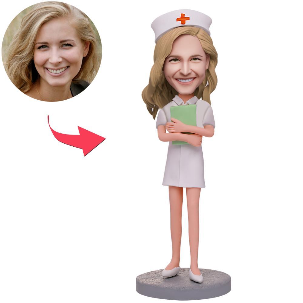 Personalised female nurse bobblehead holding a notebook, handcrafted polymer clay figure with a custom sculpted head from your photo and engraved name on the base — perfect personalised nurse gift and thank you keepsake