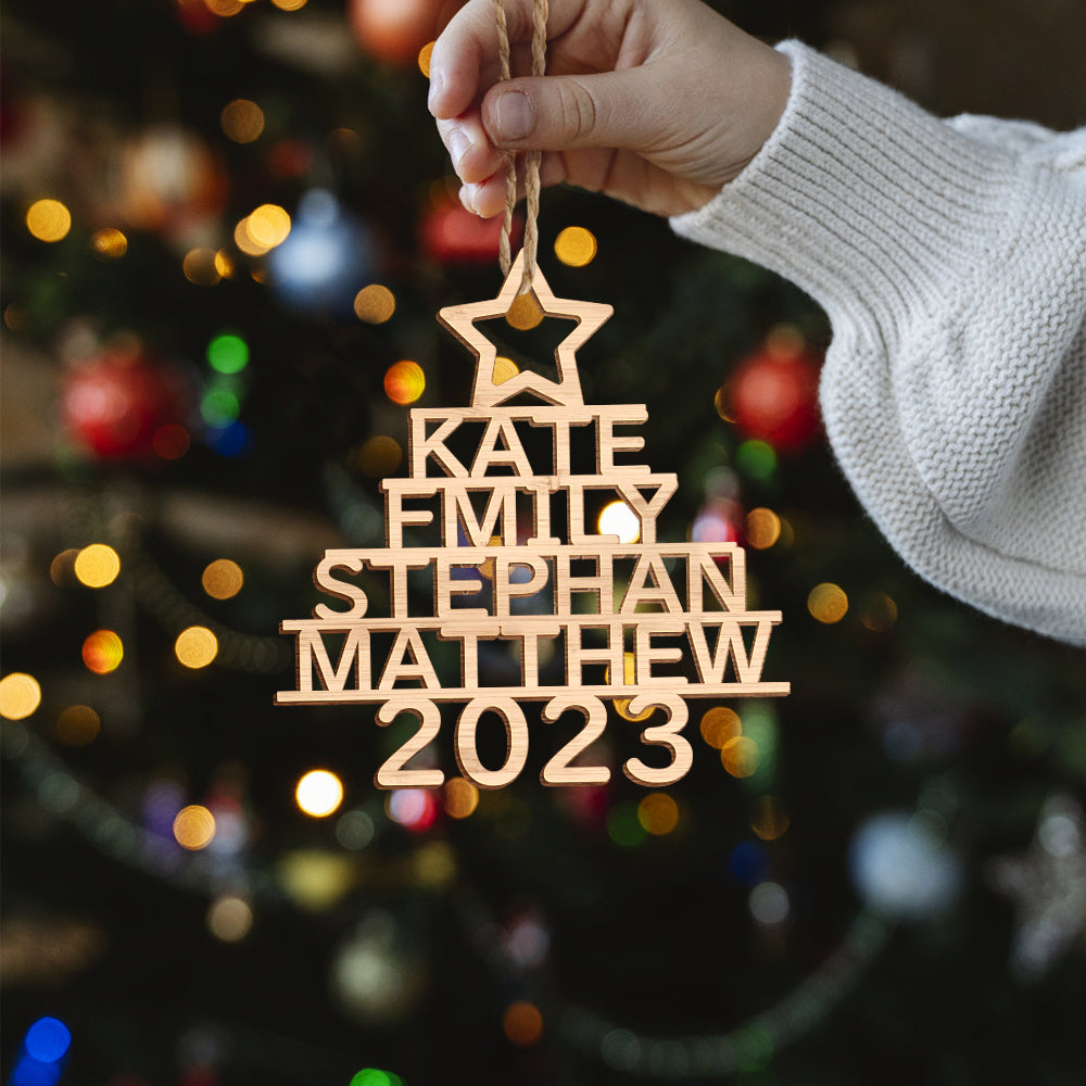 Set of personalised Christmas tree ornaments on a table showing different names and natural wood grain, custom name wooden decorations and sustainable holiday gifts