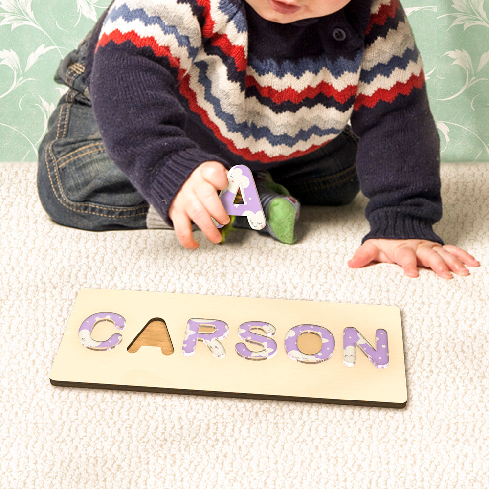 Top-down view of a personalised name puzzle showing multicoloured acrylic letters and letter cutouts for letter recognition