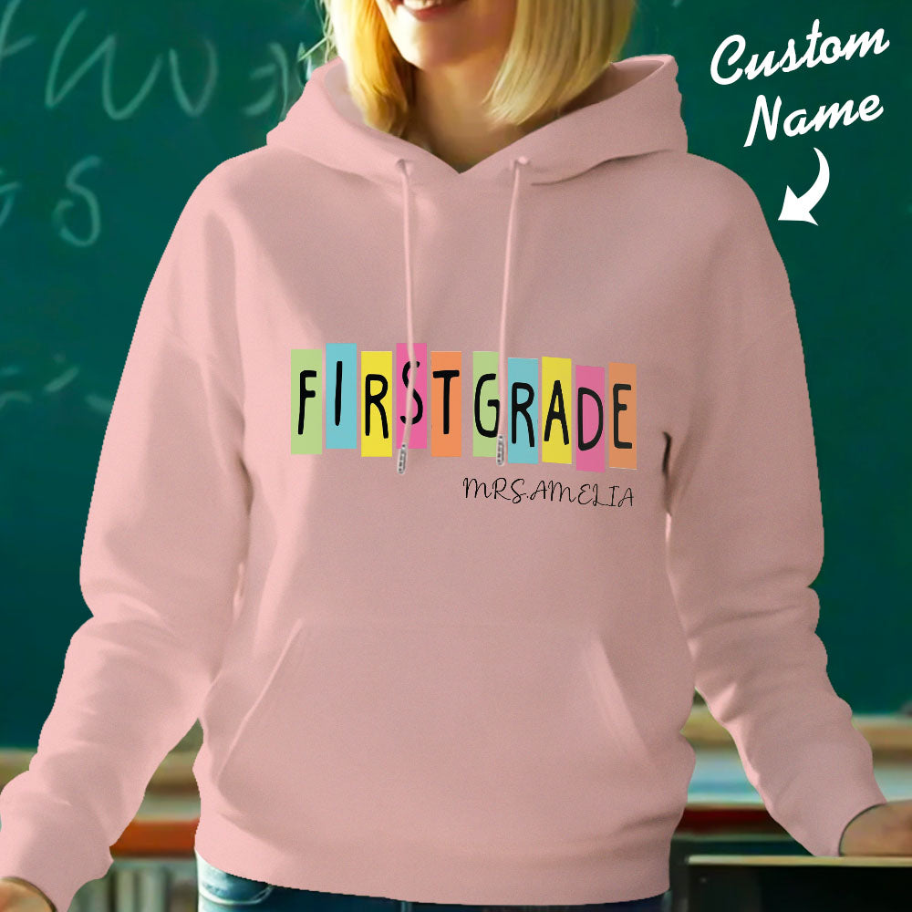 Folded personalised first grade hooded sweatshirt presented as a gift — teacher custom name hoodie, perfect for back-to-school gifting.