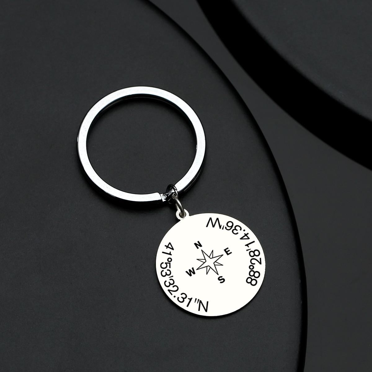 Close-up of precision engraving showing bespoke coordinates on a stainless steel keyring with integrated working compass