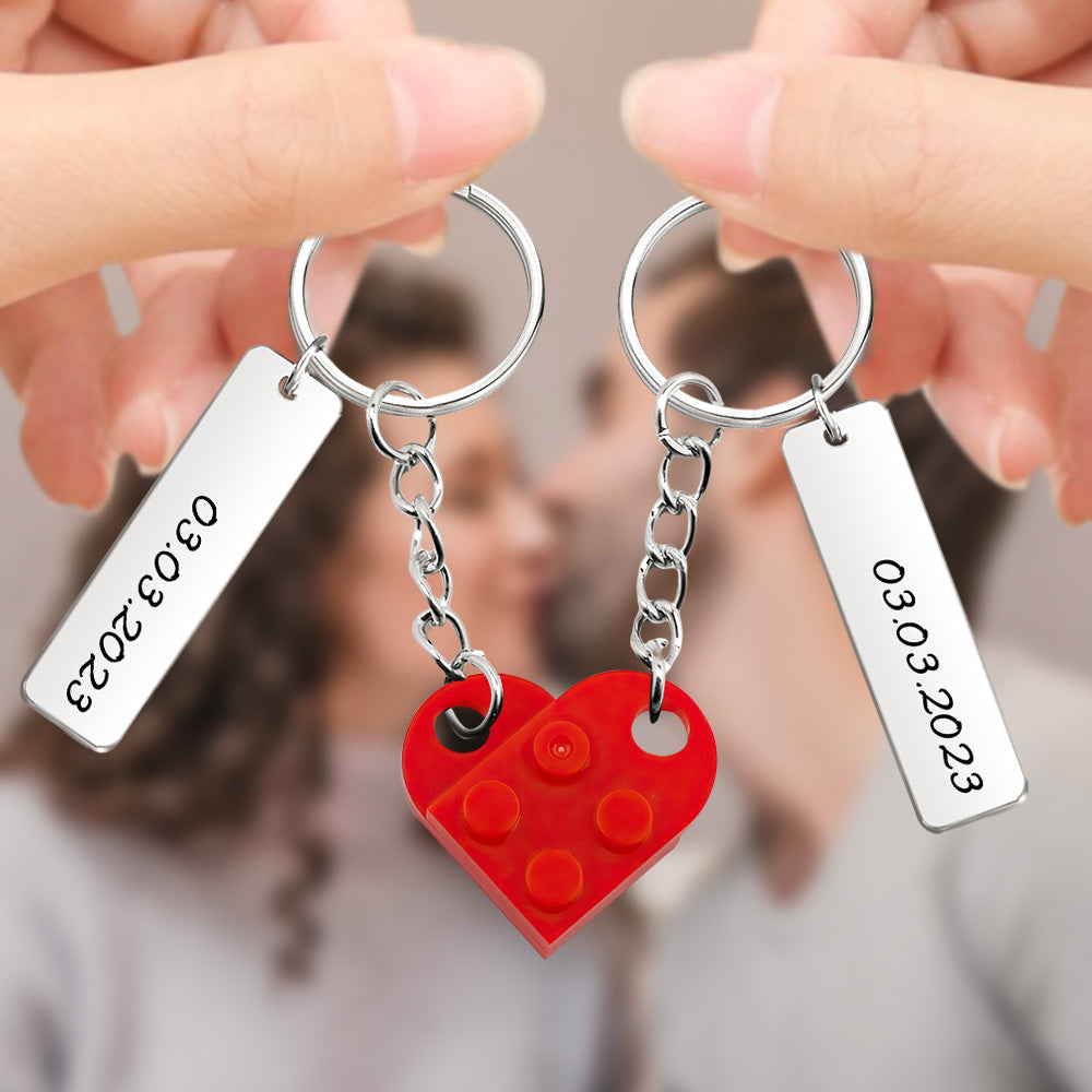 Close-up of personalised heart brick keychains showing engraved custom date and text on matching couple charms