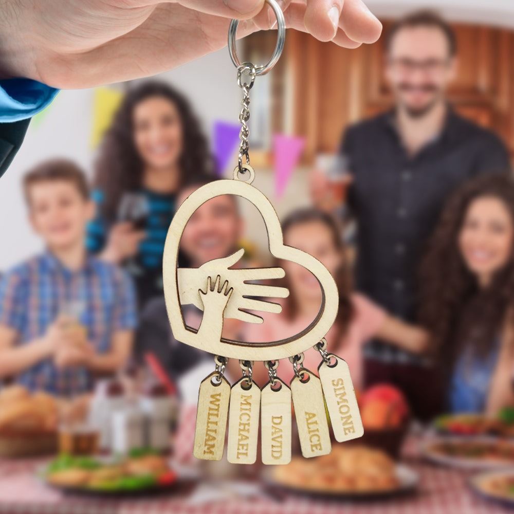 Silver-toned personalised hands keychain photographed on a rustic surface showcasing engraved family names – stylish, durable personalised gift idea