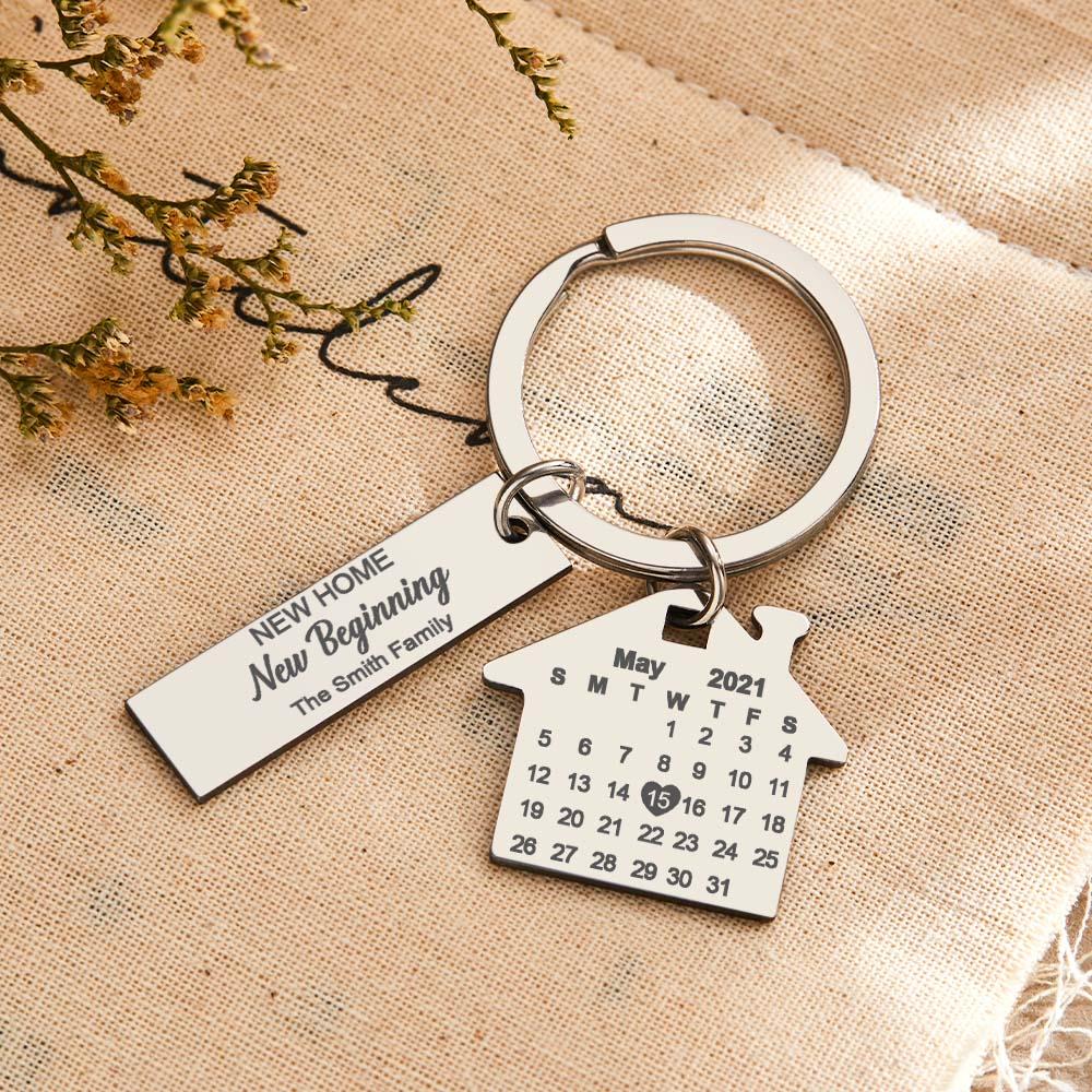 Close-up of personalised stainless steel keyring showing house and rectangular tags with precision engraving of anniversary date and name