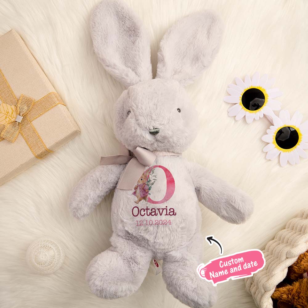 Personalised soft toy rabbit laid on a blanket, custom name embroidery visible — ideal newborn present