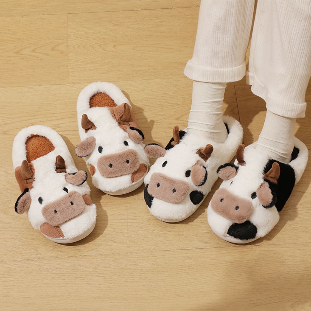 Model wearing cow cartoon animal slippers to demonstrate cosy fit and cushioned comfort for home use