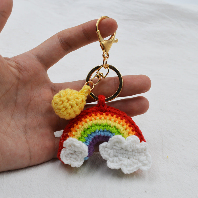 Rainbow handmade knitted keychain on plain background — cute crochet key pendant in woollen yarn with sturdy metal key ring, perfect as a bag decoration or keyring