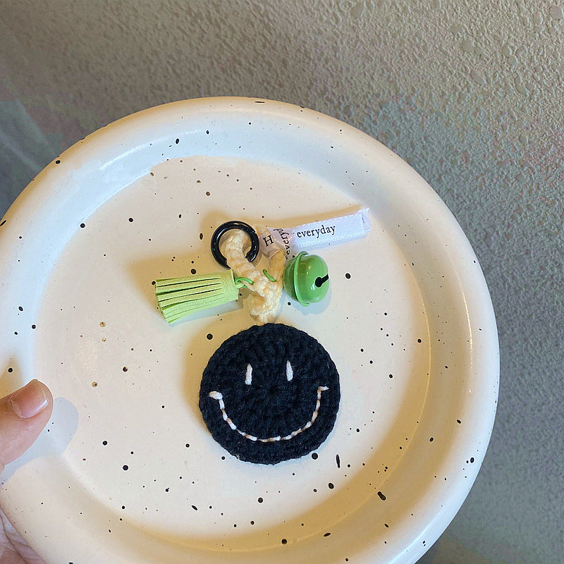 Hand holding a hand-knitted smiley face keyring — lightweight handmade crochet keychain gift for teens and women