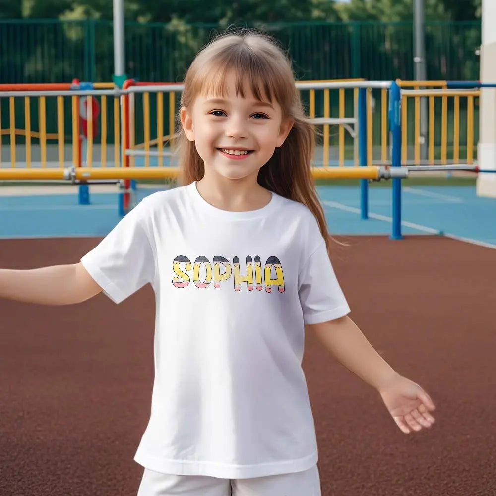 Young girl smiling in personalised pencil name T‑shirt — perfect first day of school outfit