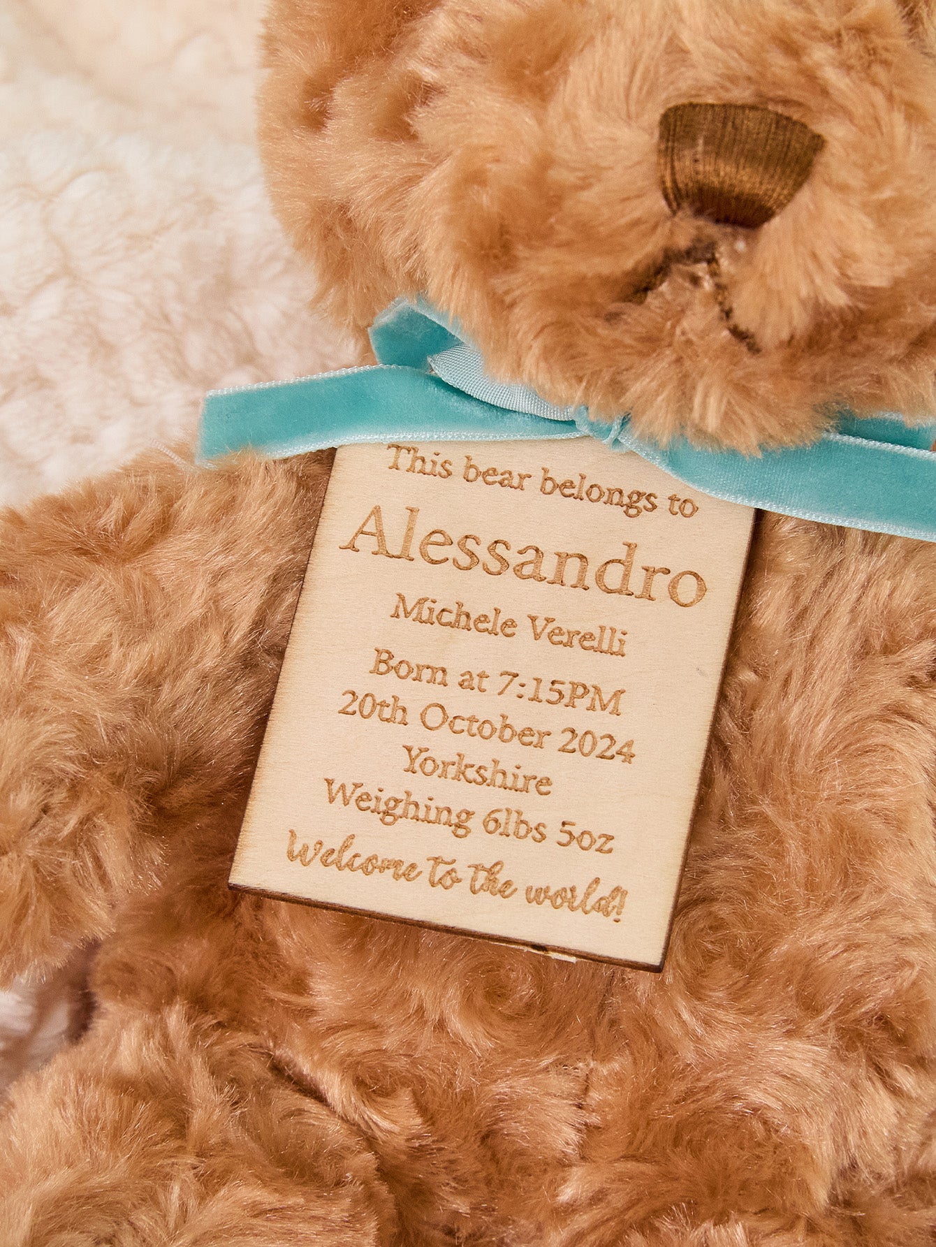 Close-up of custom embroidered birth stats on plush bear showing neat stitching and personalised name