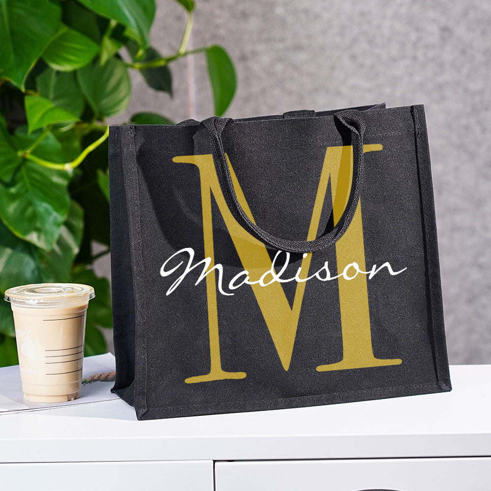 Lifestyle image of woman carrying a personalised black canvas tote with name and initial, styled as an everyday personalised gift for her