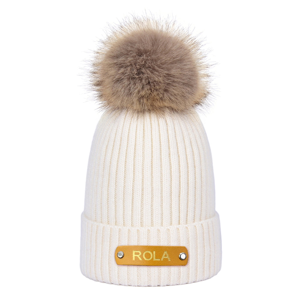 Baby wearing personalised name beanie with hot-stamped leather patch — cosy newborn winter hat ideal as a baby shower gift