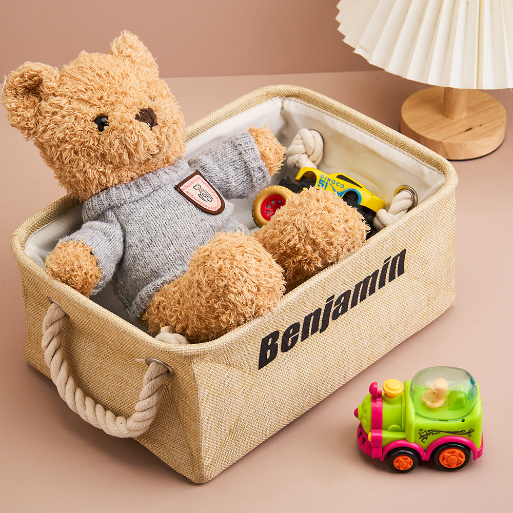 Personalised linen toy storage basket with name displayed in a nursery; open-top organiser for soft toys and books in neutral linen.