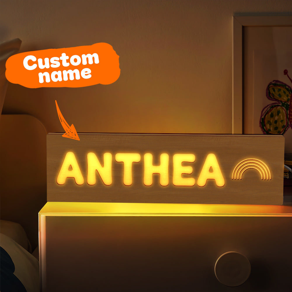Personalised wooden night light with engraved name lit on a bedside, warm LED custom nursery night light and baby shower gift