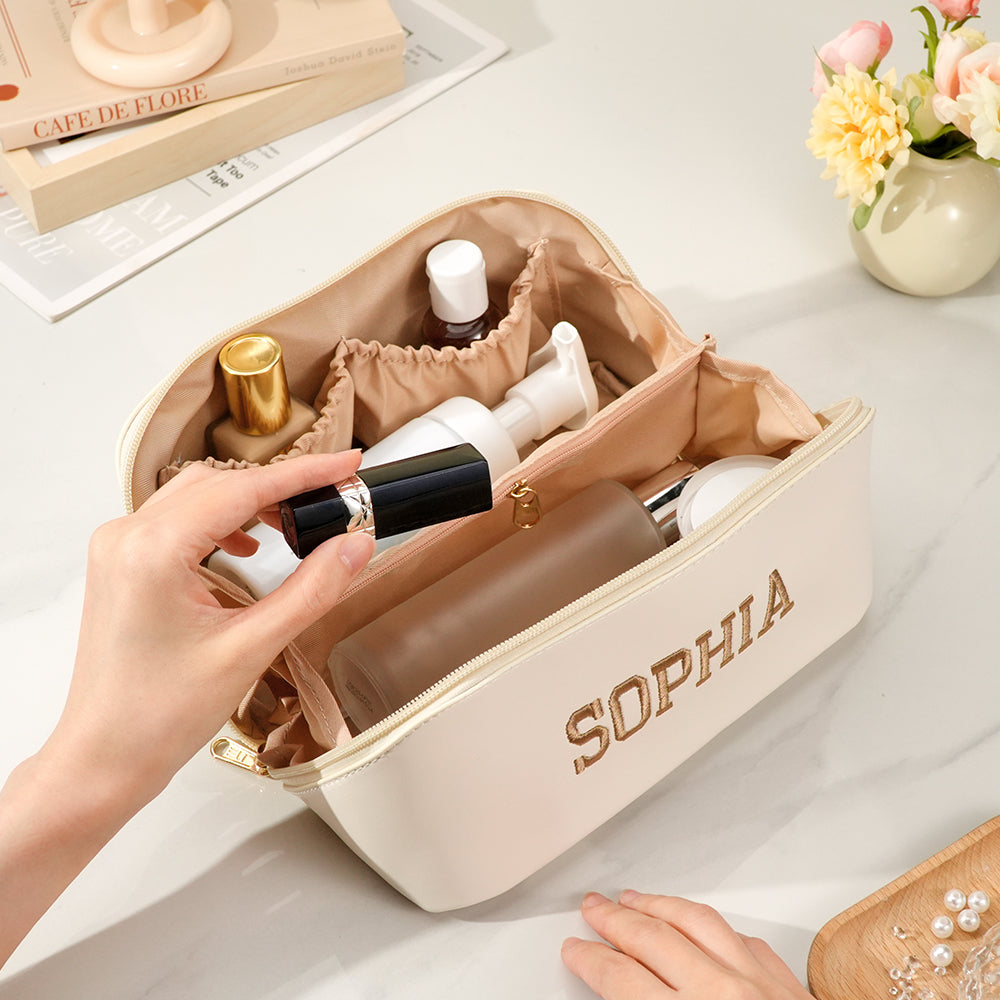 Open personalised makeup bag showing spacious interior and wipe-clean waterproof lining with embroidered name – travel cosmetics organiser