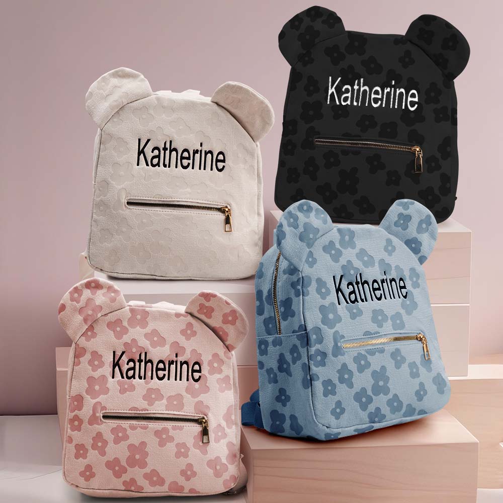 Size comparison of personalised name embroidered mini flower backpack beside a children’s book and water bottle — perfect compact canvas school bag for little hands