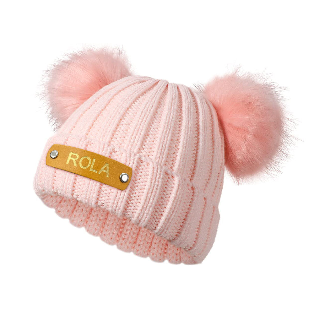 Side view of personalised baby beanie in pastel colour showing the custom name leather patch and stretchy acrylic knit