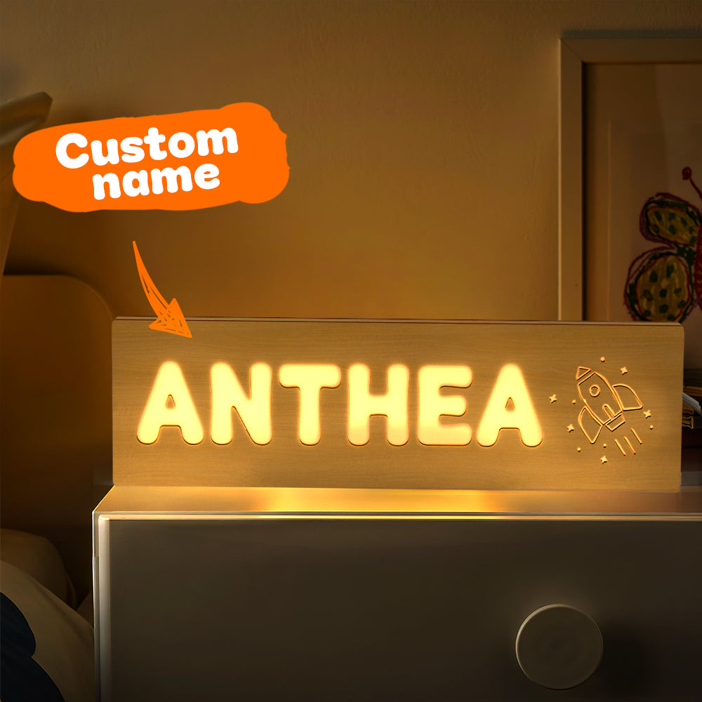 Personalised baby night light in a dimmed nursery beside a cot to illustrate cosy bedtime ambience — warm LED personalised wooden night light
