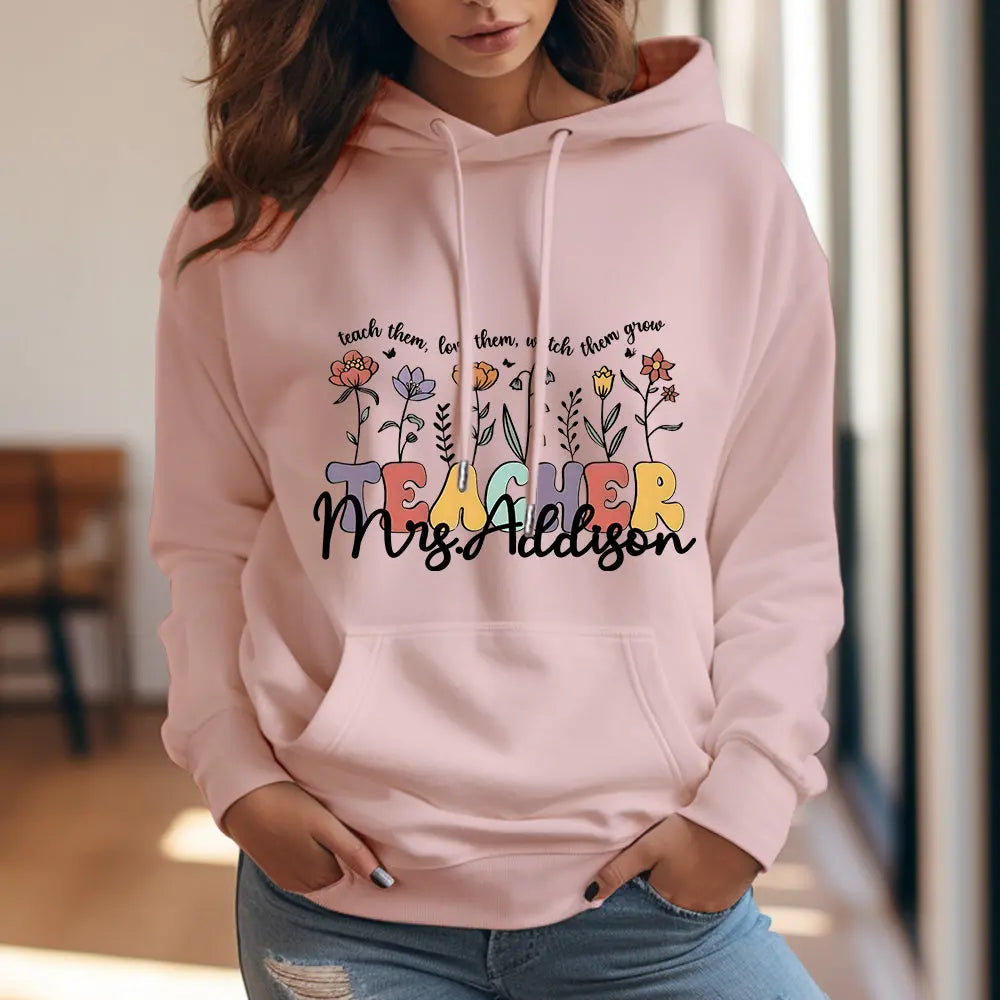Hooded sweatshirt on a hanger displaying the wildflower back print and personalised name — thoughtful personalised gifts for teachers and mums