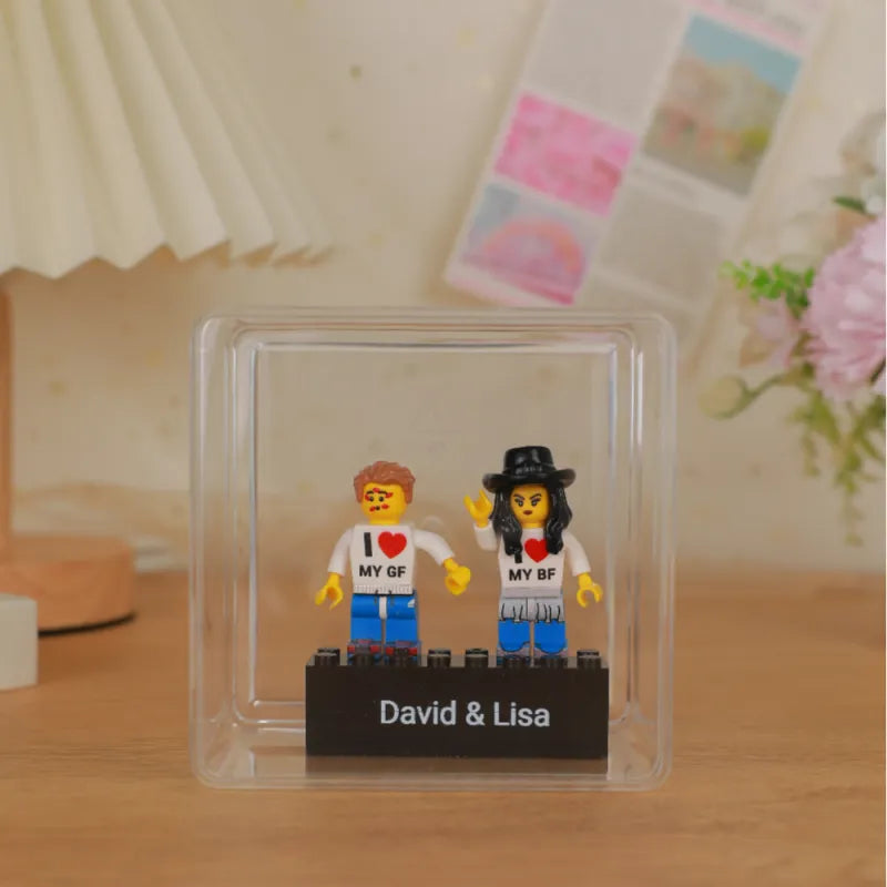 Scale view of the personalised couple minifig on its engraved base next to a hand to show compact size and display-ready design
