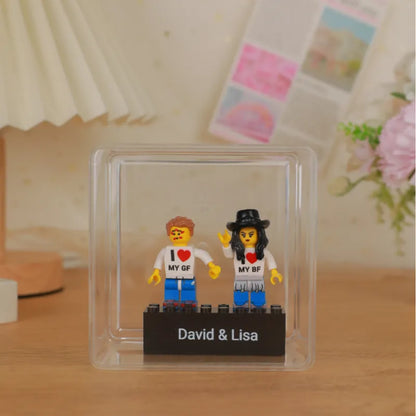 Scale view of the personalised couple minifig on its engraved base next to a hand to show compact size and display-ready design