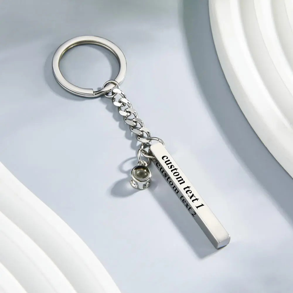Engraved cube pendant on a keyring with soft-focus background emphasizing the polished steel finish and customisation options – personalised gift for him or her
