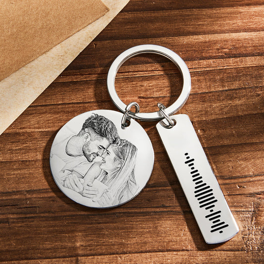 Personalised engraved stainless steel keyring showing round photo pendant, engraved calendar bar and scannable Spotify music code with a polished finish