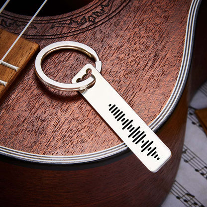 Scale photo showing stainless steel music code keyring dimensions 5 × 1 × 0.2 cm in hand to illustrate slim engraved bar size