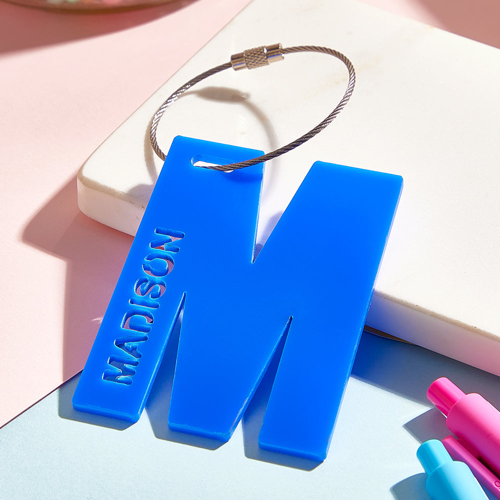 Personalised acrylic luggage tag with metal ring attachment, showing sturdy fixings for backpacks, suitcases and travel bags