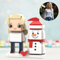 Front view of a personalised Christmas brick figure beside a fixed snowman on a festive base — small particle block toy personalised from your photo, hand-assembled ABS gift