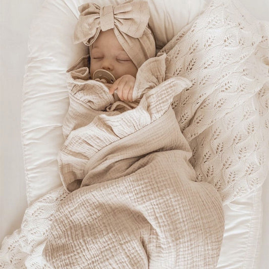 Close-up of a personalised baby swaddle blanket in soft cotton muslin with embroidered name