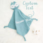 Size comparison showing a 24cm x 24cm personalised comfort towel in a baby's hand — compact, soft and ideal for cuddles and travel