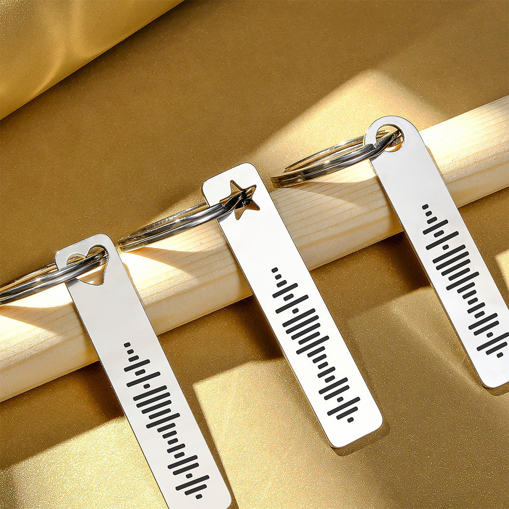 Close‑up of laser‑engraved music code on stainless steel bar keyring showing 3D bar pattern and smooth polished surface