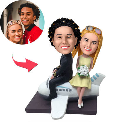 Couple On A Plane personalised bobblehead with customised heads and engraved text on the base, hand-finished polymer clay travel-themed anniversary or engagement gift
