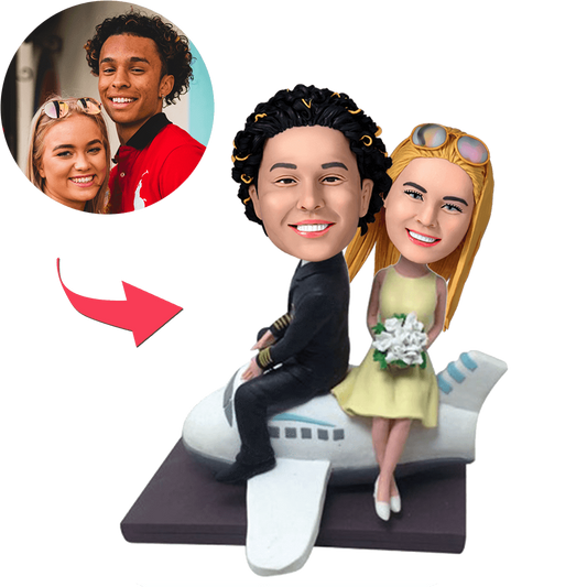 Couple On A Plane personalised bobblehead with customised heads and engraved text on the base, hand-finished polymer clay travel-themed anniversary or engagement gift