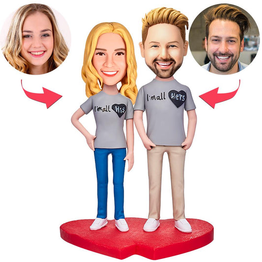Personalised couple bobbleheads in polymer clay — male and female figurines standing together with customised heads and engraved base reading 'I'm All His / Hers', ideal personalised wedding or anniversary keepsake