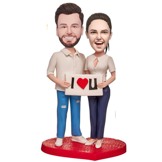 Personalised couple bobbleheads holding an engraved 'I LOVE U' sign – custom engraved text on hand-crafted polymer clay keepsake, personalised heads to match photos, perfect anniversary, wedding or Valentine's gift