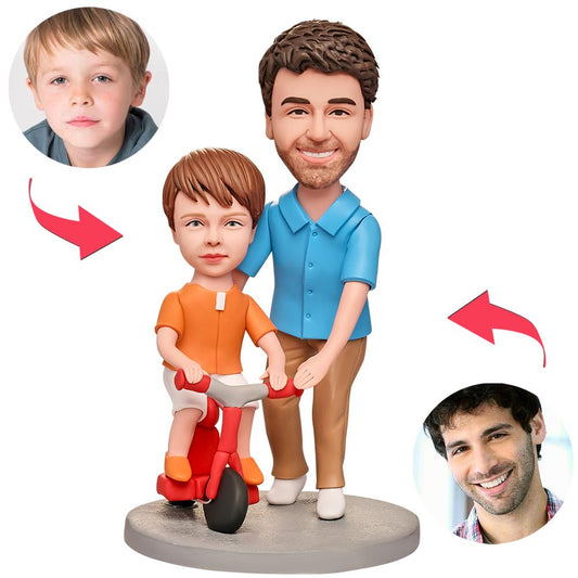 Close-up of personalised dad teaching son cycling bobblehead showing detailed facial customisation, fine polymer‑clay sculpting and engraved message on the base for a bespoke keepsake